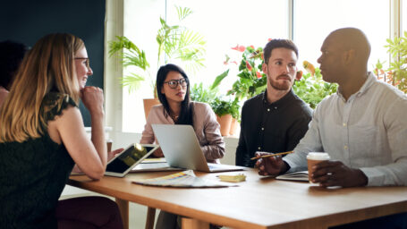 Group of focused designers having a meeting together while sitting around a table in the boardroom of a modern office