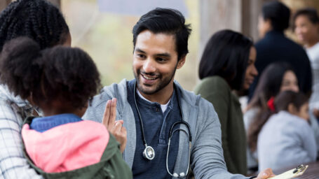 Doctor checks a young patient's vision at an outdoor clinic